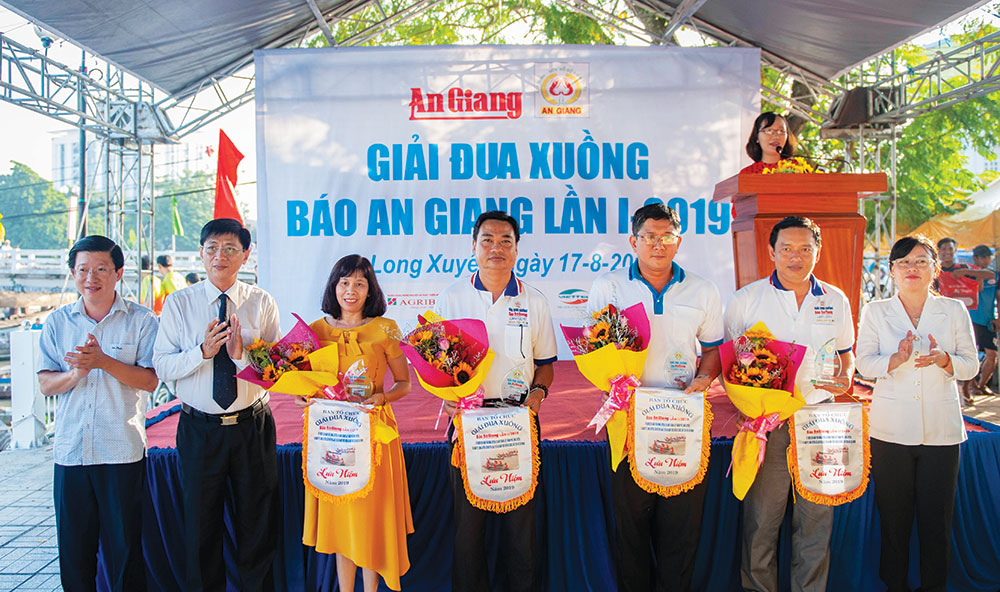 Sôi nổi giải đua xuồng Báo An Giang lần thứ I - 2019 Phó Tổng biên tập Báo An Giang Đào Thị Dạ Thảo và Nguyễn Hoàng Anh Tuấn cùng Phó Chủ tịch UBND TP. Long Xuyên Nguyễn Phú tặng hoa và cờ lưu niệm cho các đơn vị tài trợ